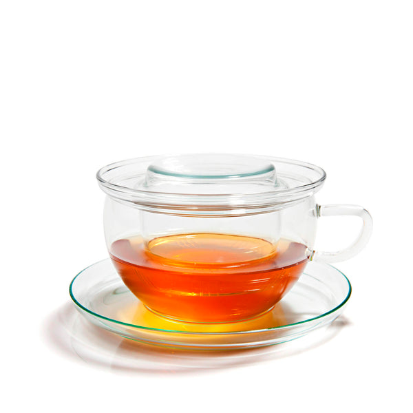 Glass tea cup with infuser sitting on glass saucer